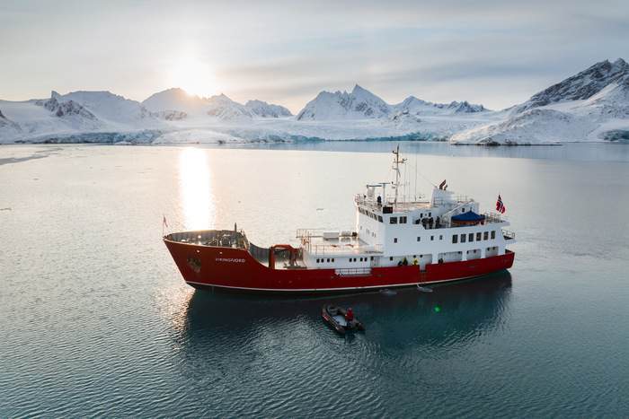 MV Vikingfjord in Svalbard with Zodiac and sun in background Secret Atlas..jpg